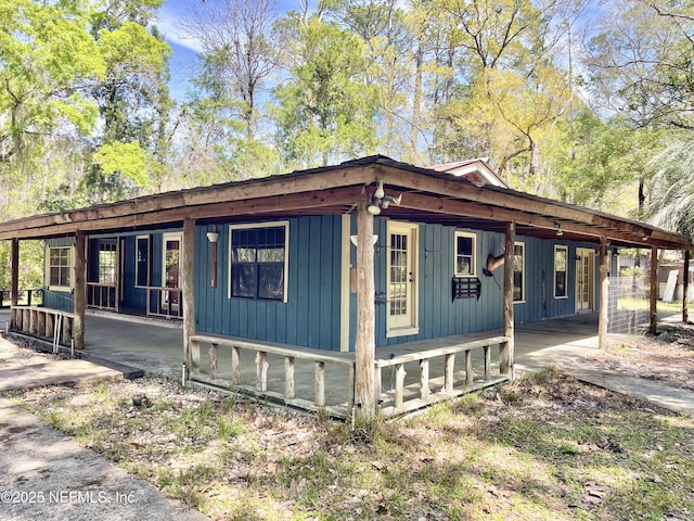 exterior space featuring board and batten siding, a carport, and covered porch