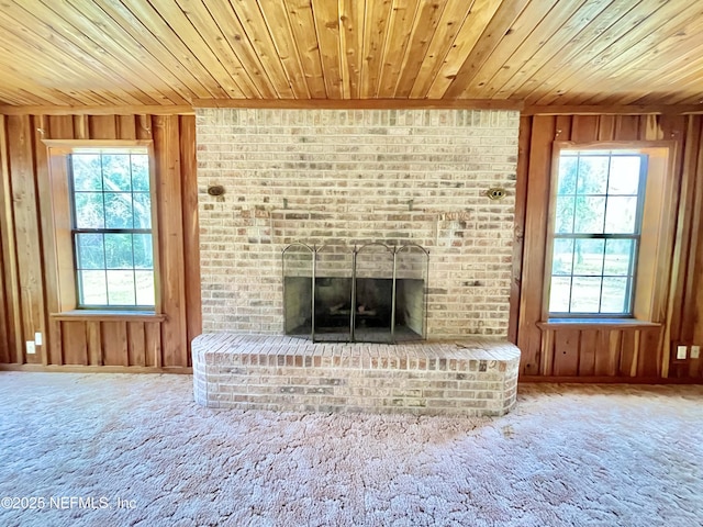 unfurnished living room with plenty of natural light, a fireplace, wooden ceiling, and wooden walls