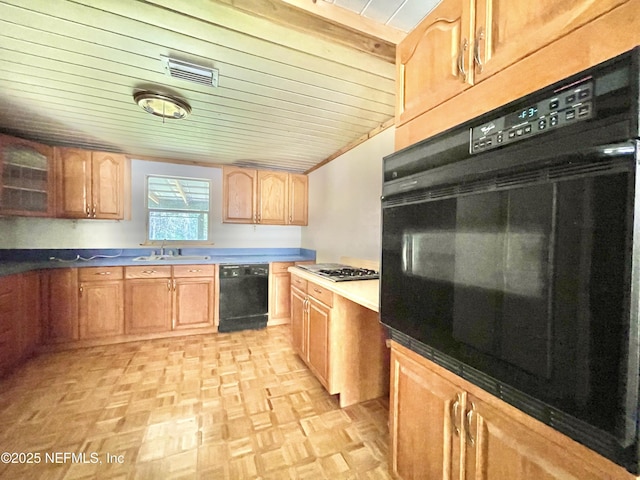 kitchen featuring a sink, visible vents, glass insert cabinets, and black appliances