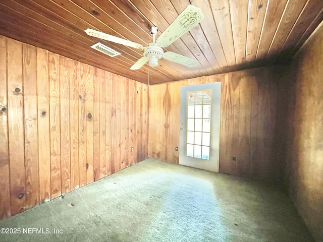 carpeted spare room with visible vents, wood walls, wooden ceiling, and a ceiling fan