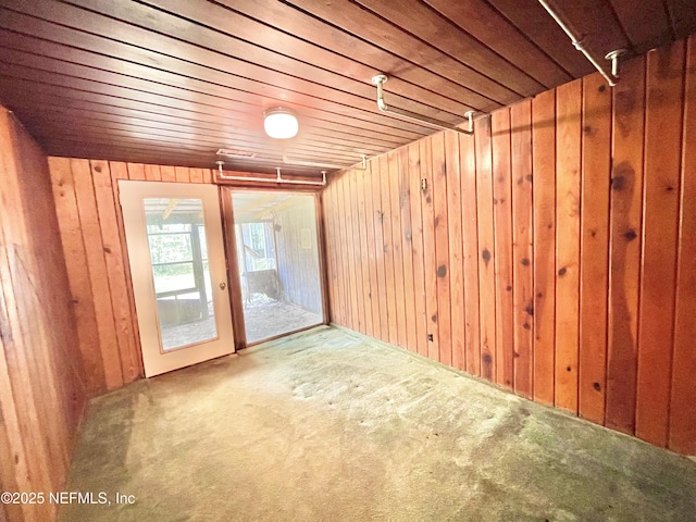 carpeted spare room with wood walls and wooden ceiling