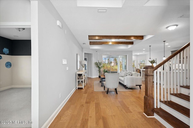 entrance foyer with visible vents, baseboards, beamed ceiling, stairs, and light wood-style flooring