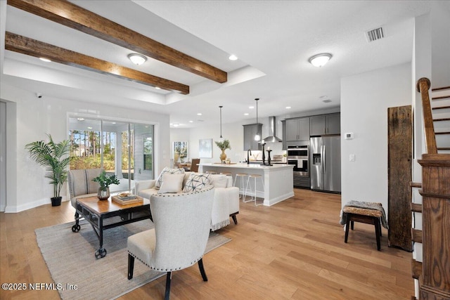 living area with stairway, visible vents, light wood finished floors, recessed lighting, and beamed ceiling