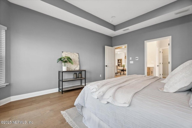 bedroom with visible vents, wood finished floors, and baseboards