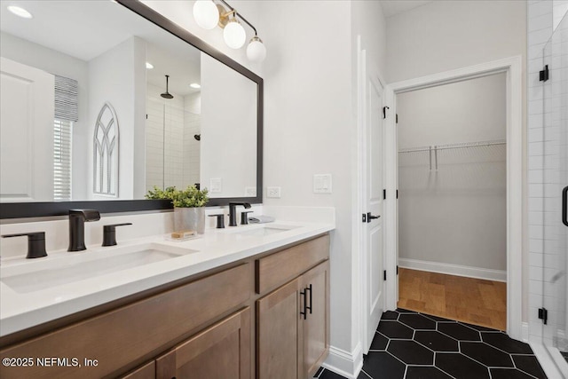 full bath featuring a spacious closet, a shower stall, double vanity, and a sink