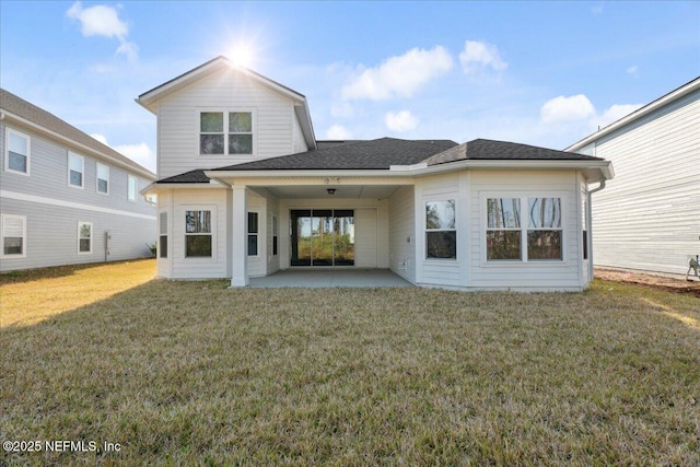 back of property with a patio, a yard, and roof with shingles