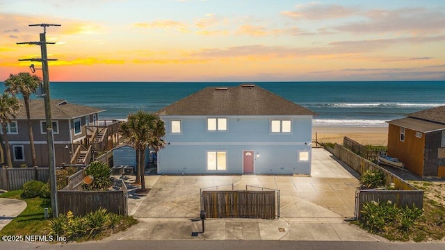 view of front facade featuring a fenced backyard, a view of the beach, a water view, and a patio area