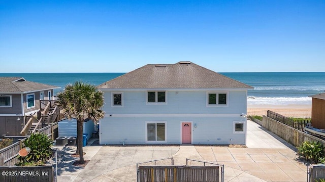 back of house featuring a patio area, roof with shingles, a fenced backyard, and a water view