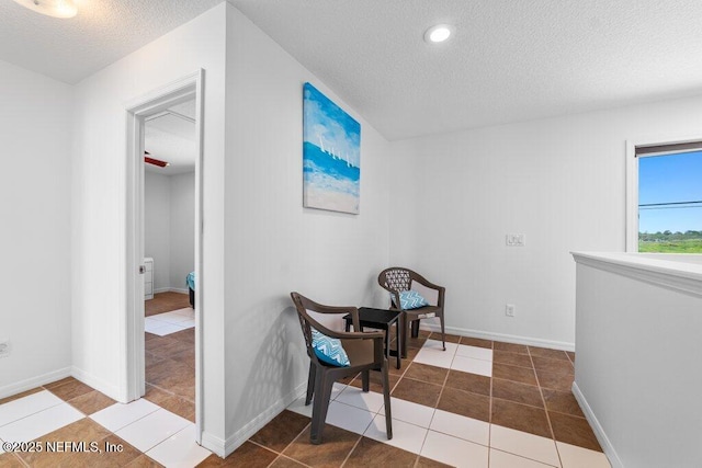 hall featuring tile patterned flooring, baseboards, a textured ceiling, and recessed lighting