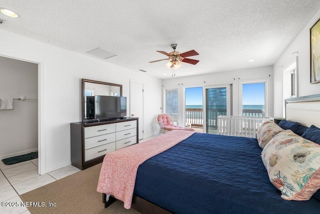 bedroom with a textured ceiling, light tile patterned floors, ceiling fan, access to outside, and visible vents