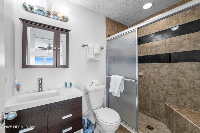 full bath with a shower stall, toilet, vanity, and a textured ceiling
