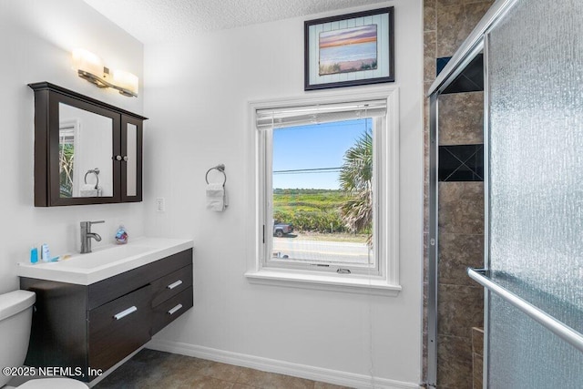 full bathroom featuring toilet, vanity, baseboards, a textured ceiling, and tiled shower