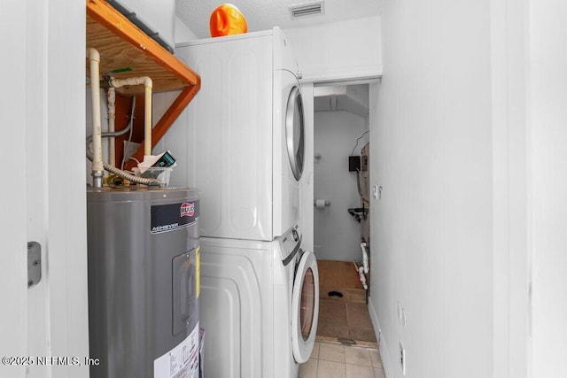 clothes washing area with electric water heater, light tile patterned flooring, laundry area, stacked washer and dryer, and visible vents