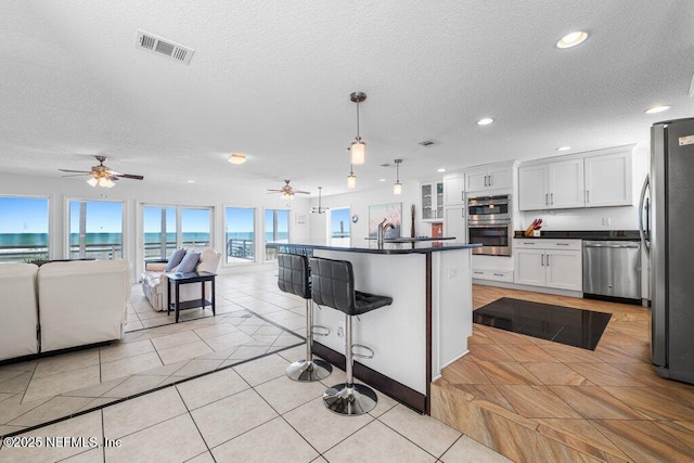 kitchen featuring stainless steel appliances, a ceiling fan, open floor plan, and dark countertops