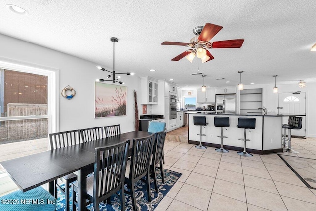 dining room with a textured ceiling, ceiling fan, and light tile patterned floors