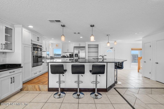 kitchen with dark countertops, visible vents, appliances with stainless steel finishes, and plenty of natural light
