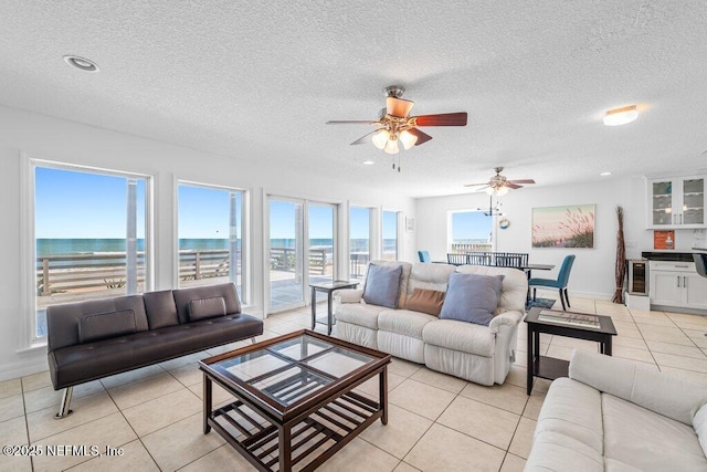living area featuring ceiling fan, a textured ceiling, wine cooler, and light tile patterned floors
