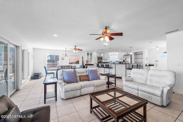 living area with a textured ceiling, visible vents, ceiling fan, and light tile patterned floors