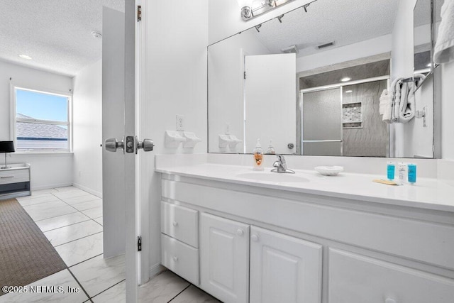 bathroom featuring vanity, a textured ceiling, marble finish floor, and a stall shower