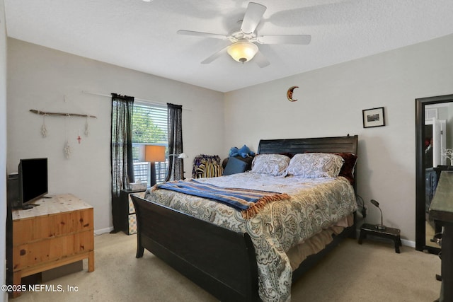 bedroom featuring ceiling fan, a textured ceiling, baseboards, and light carpet