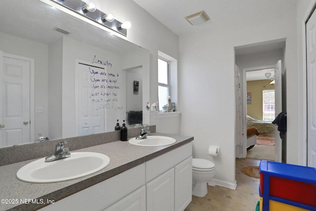 ensuite bathroom with toilet, visible vents, and a sink