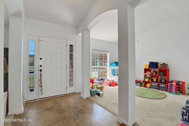 entrance foyer with baseboards, arched walkways, and carpet flooring