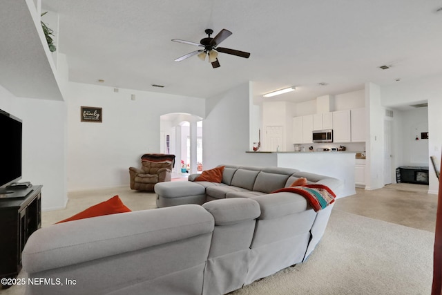 living area featuring arched walkways and ceiling fan