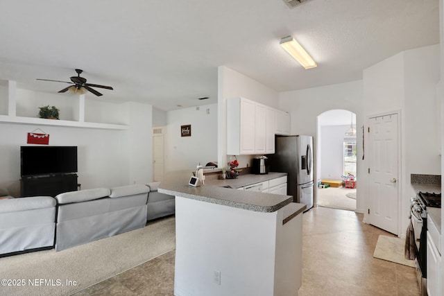 kitchen with arched walkways, ceiling fan, stainless steel refrigerator with ice dispenser, gas range, and open floor plan