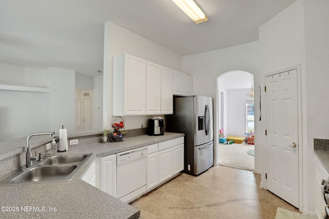 kitchen with dishwasher, stainless steel refrigerator with ice dispenser, arched walkways, white cabinets, and a sink