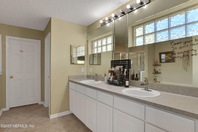 bathroom with tile patterned floors, a shower with shower door, a textured ceiling, and a sink