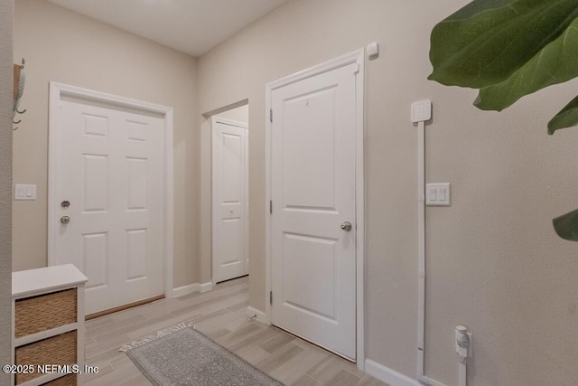 corridor featuring baseboards and light wood finished floors