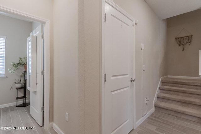 hall featuring stairs, baseboards, and wood tiled floor