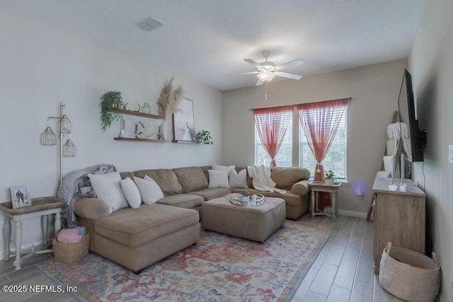 living area featuring baseboards, wood finished floors, visible vents, and ceiling fan