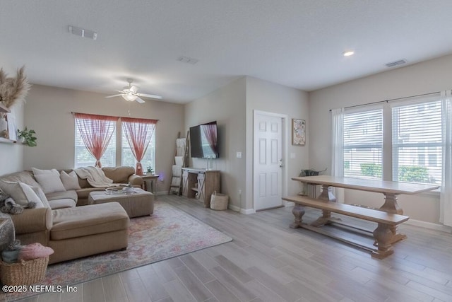 living area featuring visible vents, ceiling fan, and wood finished floors