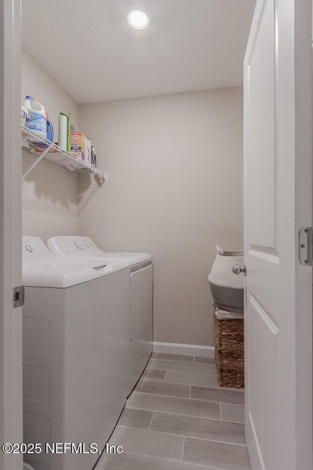 laundry room with washer and clothes dryer, laundry area, baseboards, and wood finish floors