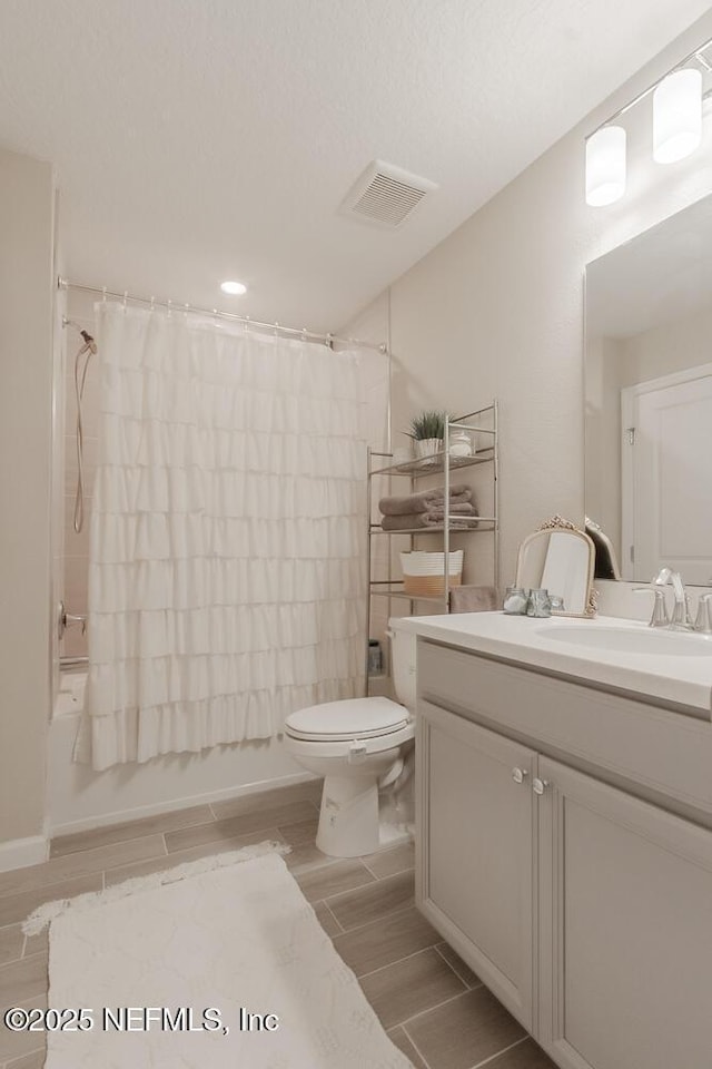 full bath featuring wood finish floors, visible vents, toilet, shower / bath combination with curtain, and vanity