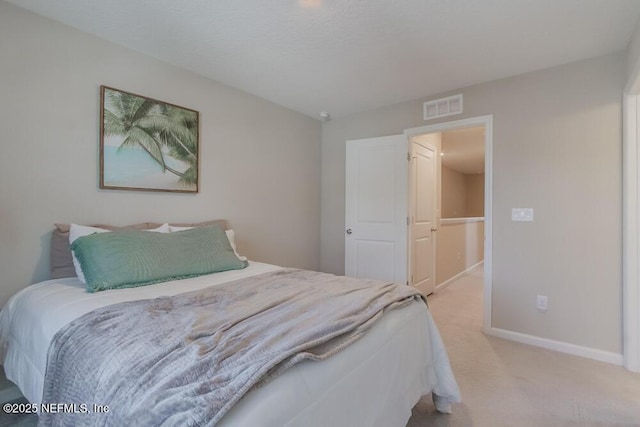 bedroom featuring visible vents, light colored carpet, and baseboards