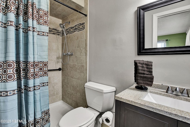 bathroom featuring tiled shower, toilet, and vanity