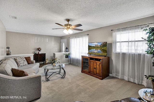 living area with visible vents, carpet floors, a healthy amount of sunlight, and ceiling fan