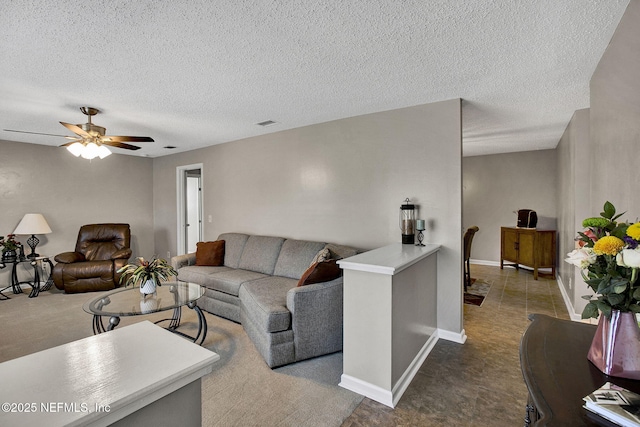 living area with a textured ceiling, visible vents, baseboards, and ceiling fan