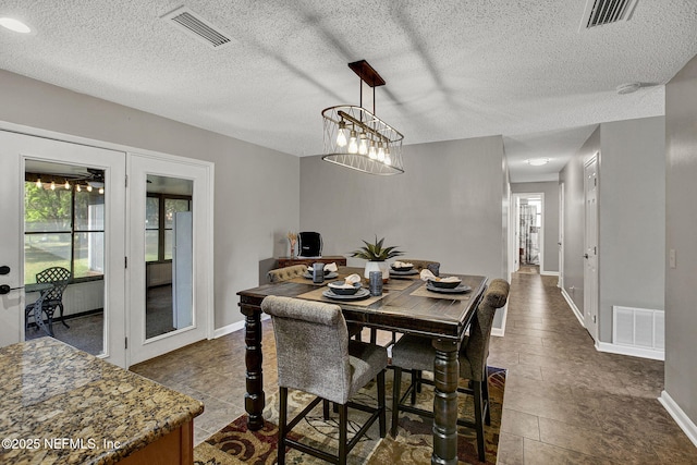 dining room with visible vents, baseboards, and a textured ceiling