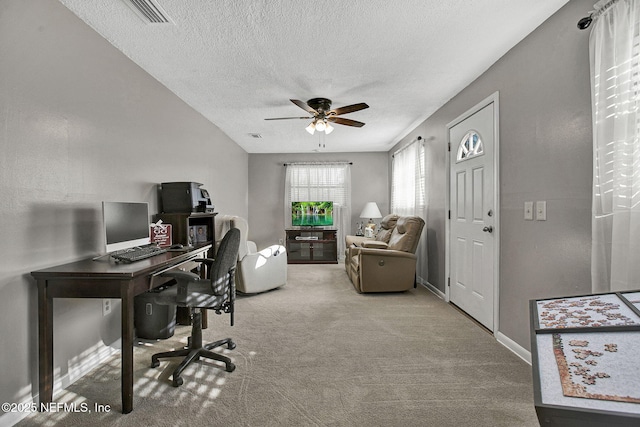 carpeted office space featuring visible vents, baseboards, a textured ceiling, and ceiling fan