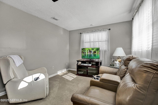 living room with visible vents, baseboards, a textured ceiling, and carpet flooring