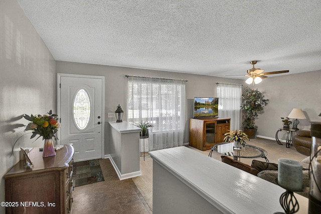 foyer entrance featuring baseboards, a textured ceiling, and a ceiling fan