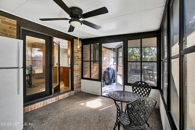 unfurnished sunroom with ceiling fan