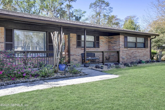 ranch-style house featuring a porch, brick siding, and a front lawn