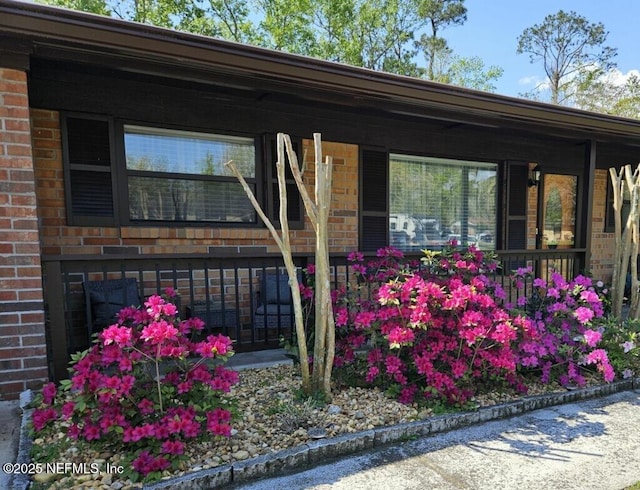 entrance to property with brick siding and a porch