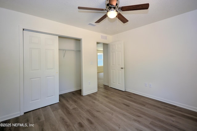 unfurnished bedroom featuring visible vents, a textured ceiling, wood finished floors, a closet, and baseboards