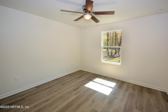 empty room featuring baseboards, wood finished floors, and a ceiling fan