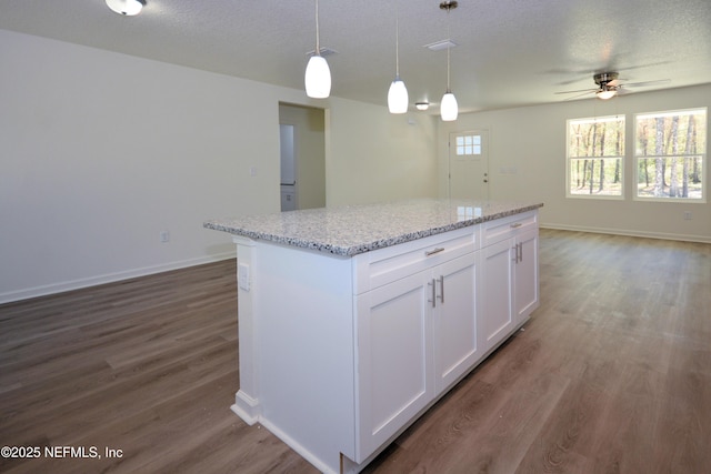 kitchen with a kitchen island, a textured ceiling, dark wood-style floors, and white cabinetry